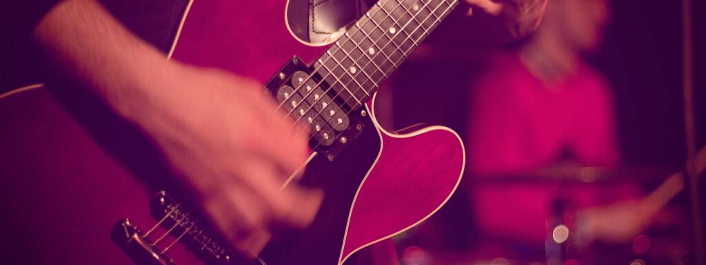 A close up of a band member playing electric guitar