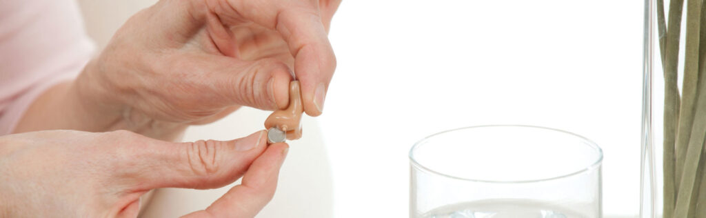 A female audiologist replacing hearing aid batteries